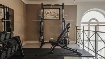 A gym with weightlifting equipment, a bench, and a framed picture on the wall.