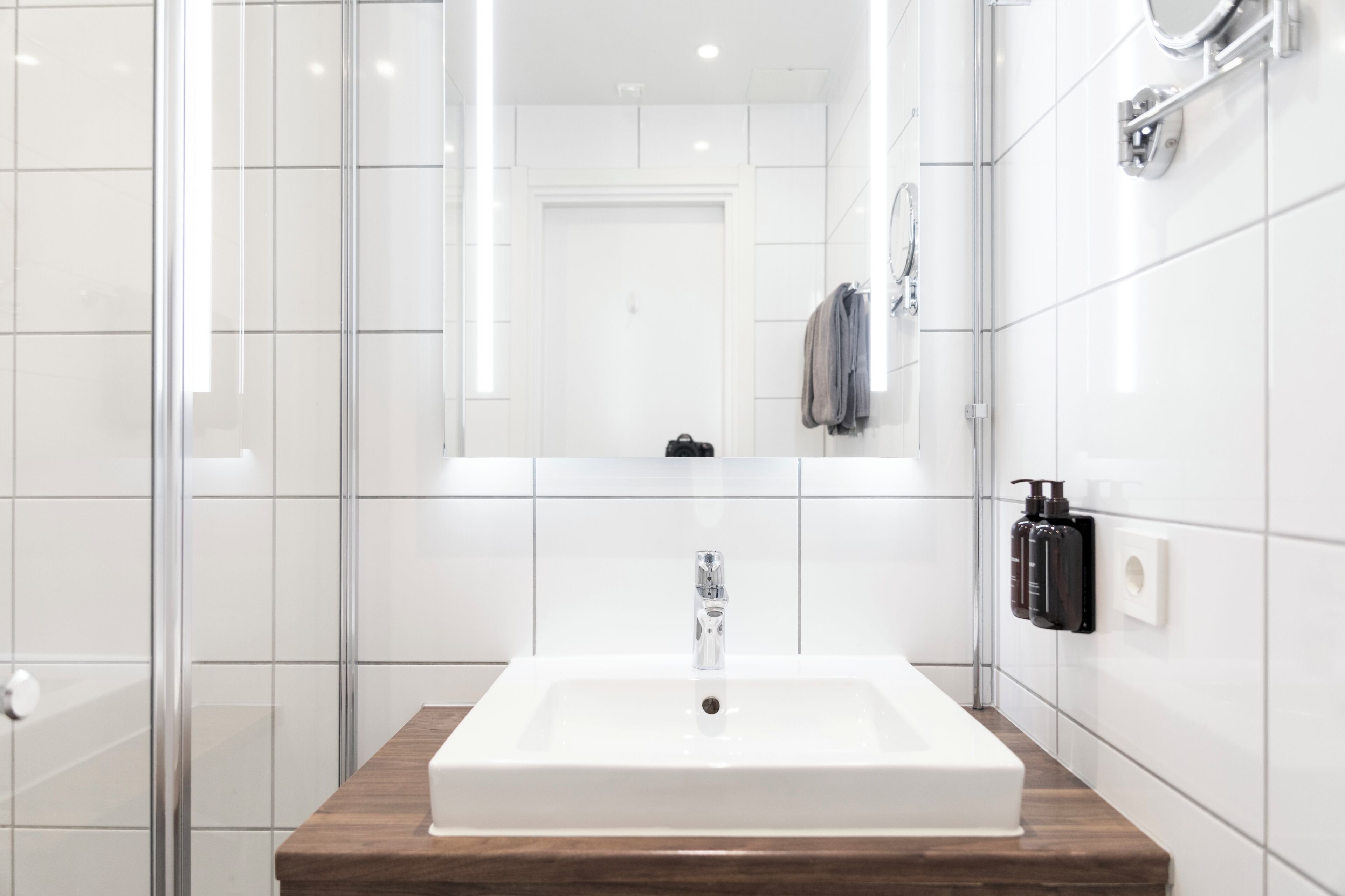 A modern bathroom with a rectangular sink, a glass shower enclosure, and a mirror above the sink.