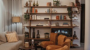 A living room with a sofa, two armchairs, a coffee table, a TV, and a bookshelf filled with books and decorative items.