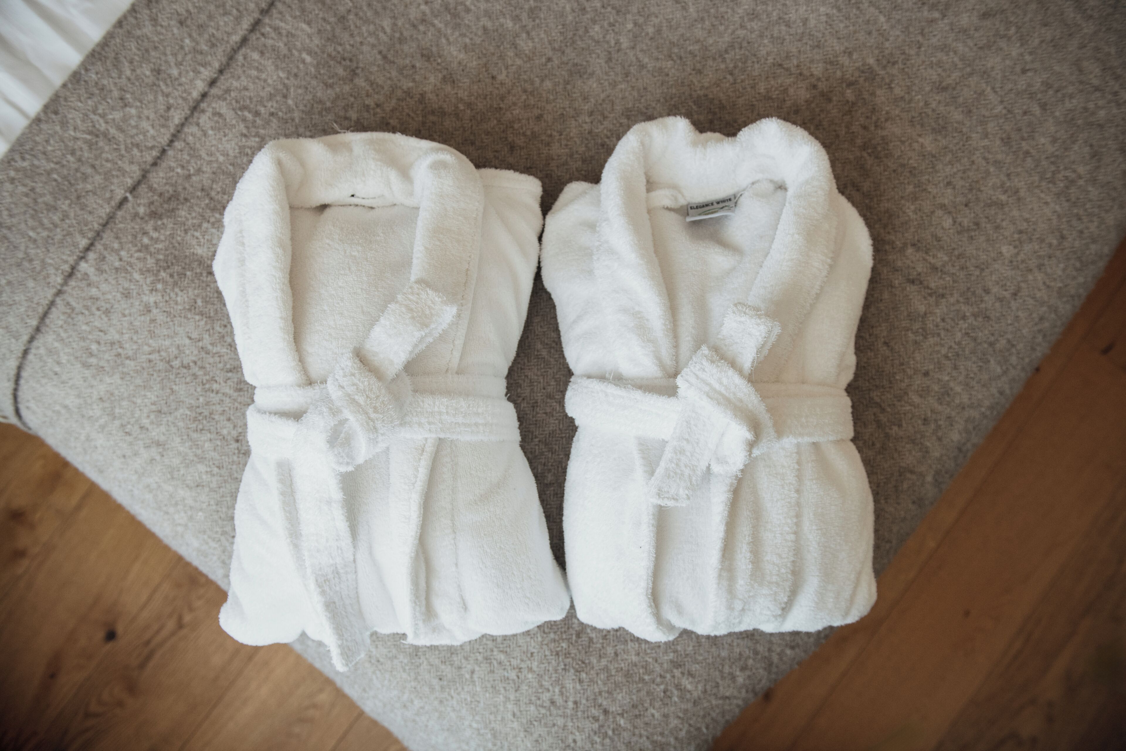 Deux peignoirs blancs posés sur un tapis beige.