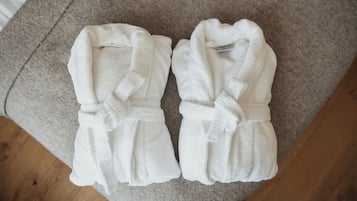 Deux peignoirs blancs posés sur un tapis beige.