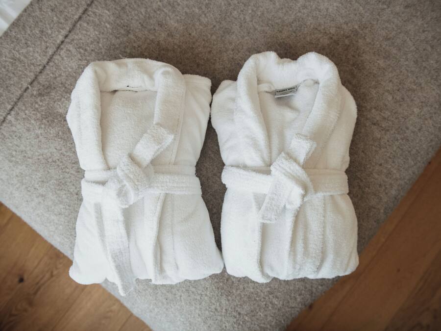 Deux peignoirs blancs posés sur un tapis beige.