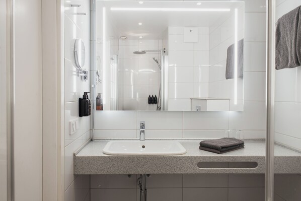 Un baño moderno con lavamanos, espejo e inodoro con ducha.