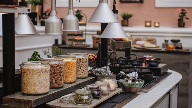 A kitchen counter with various food containers, hanging kitchen lights, and a window in the background.