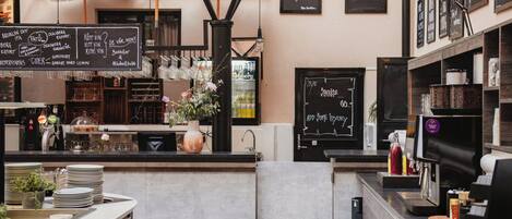 A bar area with a chalkboard menu, a coffee machine, and a sign that reads 'HOME HOTEL VICTORIA'.