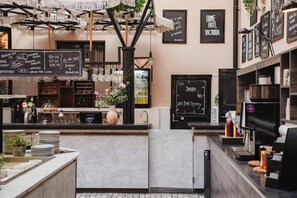 A bar area with a chalkboard menu, a coffee machine, and a sign that reads 'HOME HOTEL VICTORIA'.
