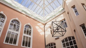A building with a glass ceiling, arched windows, and a geometric light fixture.
