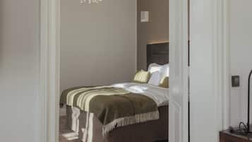 A bedroom with a bed, a chandelier, and a bedside table.