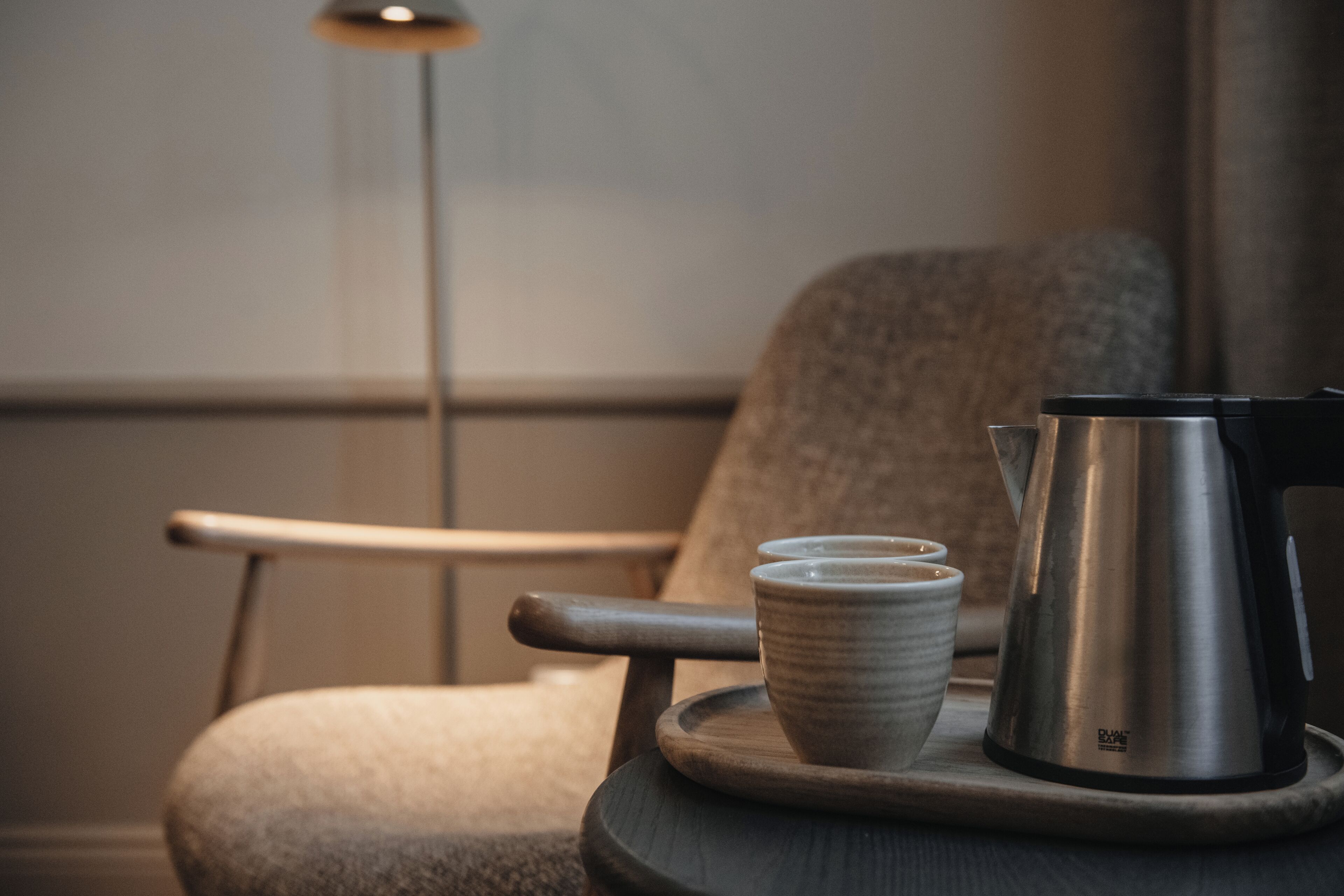 Una silla con una bandeja que sostiene una cafetera y dos tazas.