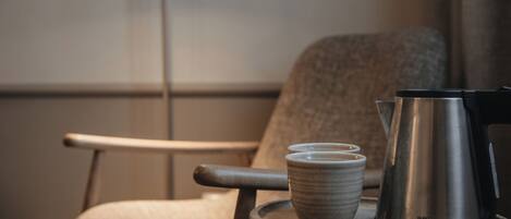 Una silla con una bandeja que sostiene una cafetera y dos tazas.