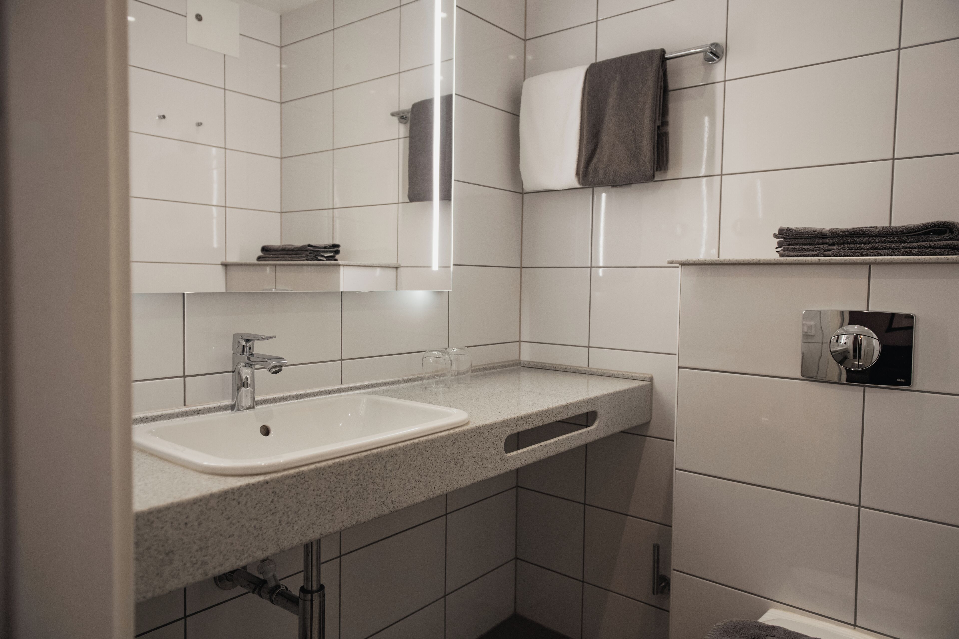 Een badkamer met een wastafel, spiegel, handdoekrek en toilet.