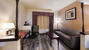 Una habitación de hotel con una silla de madera, un sofá, un escritorio y una lámpara.