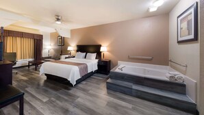 Una habitación de hotel con cama, mesitas de noche, escritorio, silla, un amplio ventanal con cortinas, bañera y zona de ducha.