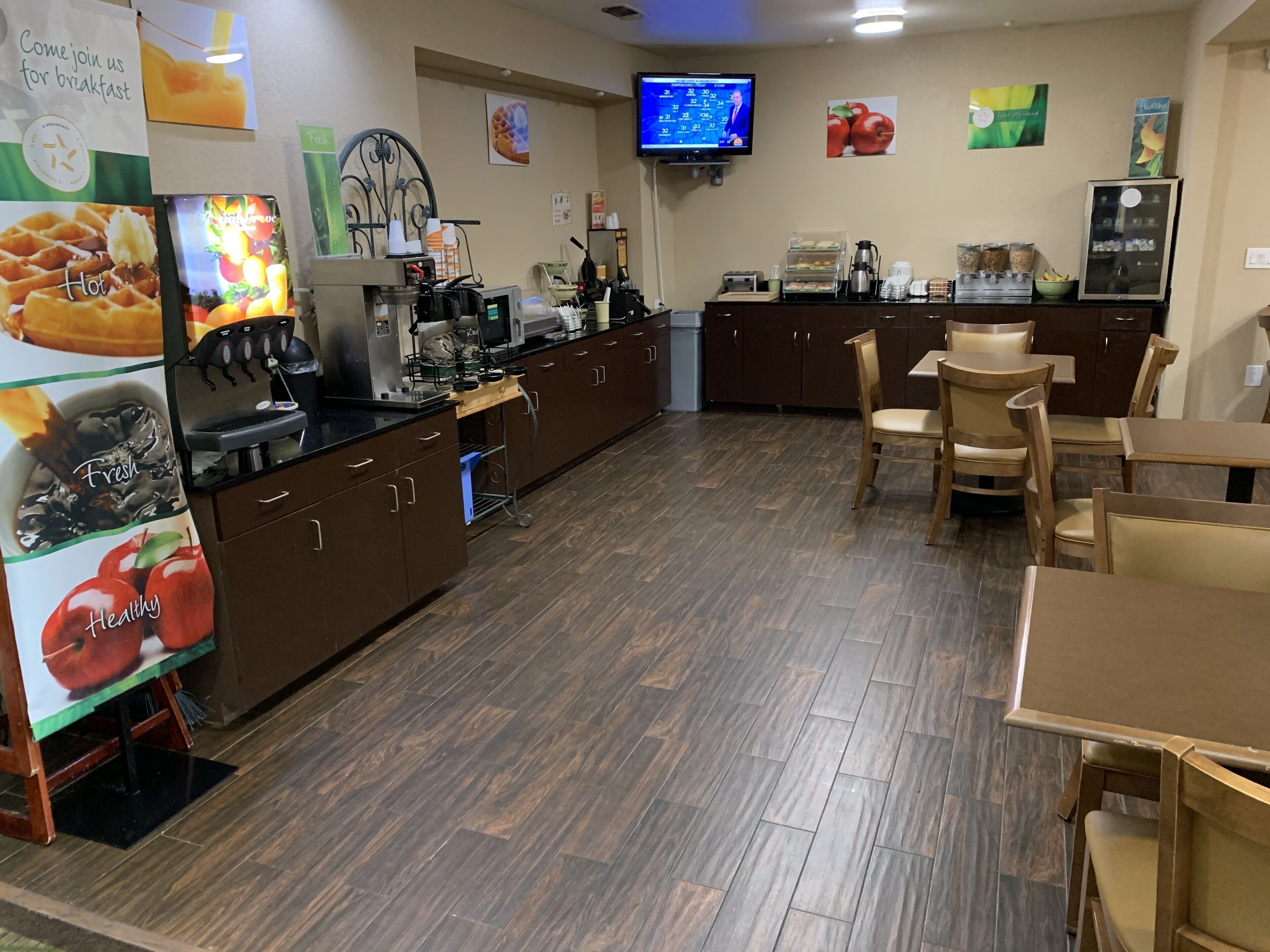 A breakfast area with a counter, coffee machines, and seating.