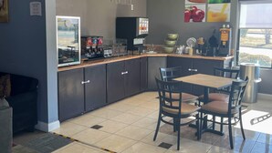 A modern kitchen with a dining area, equipped with a coffee machine, a refrigerator, and a window with a view. - Quality Suites Abilene Mall Area (Abilene)