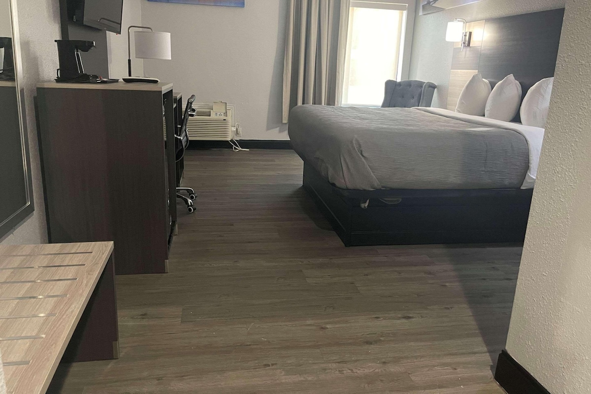 A hotel room with a bed, desk, chair, and a television on the wall.