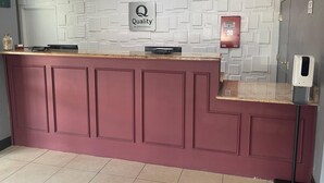 A reception desk with a 'Quality by Choice Hotels' sign, a fire alarm, and a hand sanitizer dispenser. - Quality Suites Abilene Mall Area (Abilene)