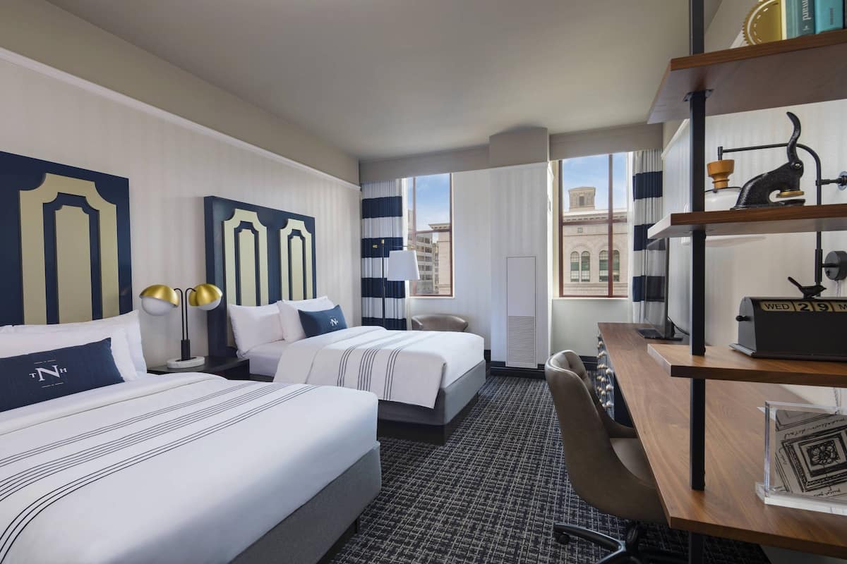 Une chambre d’hôtel avec deux lits, un bureau et une chaise.
