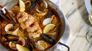 A seafood paella dish with shrimp, mussels, clams, and lemon slices.