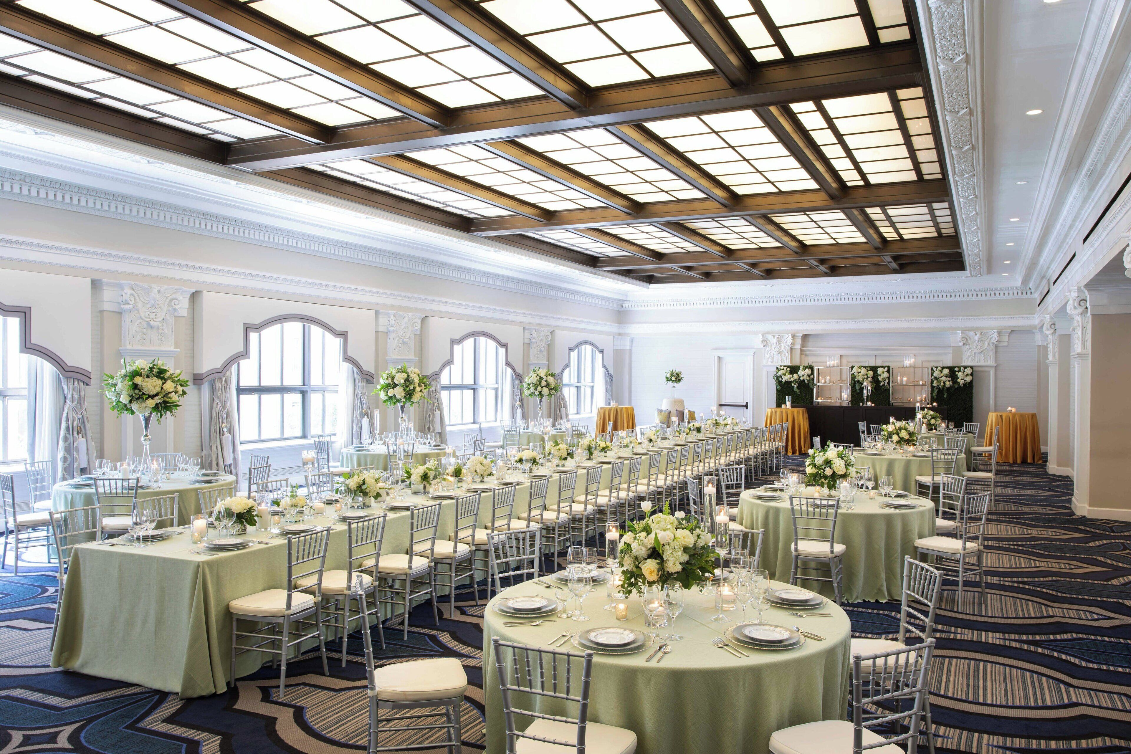 A banquet hall with round tables set for dining, featuring white tablecloths and floral centerpieces.