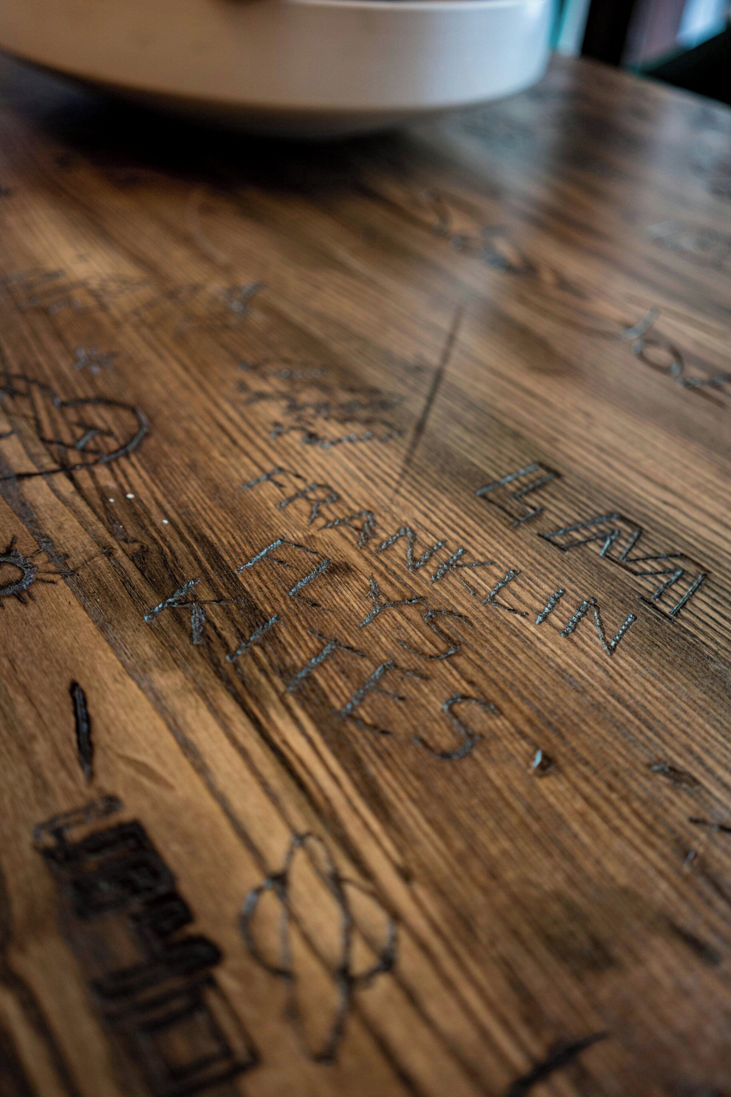 Una superficie de madera con texto y símbolos grabados.