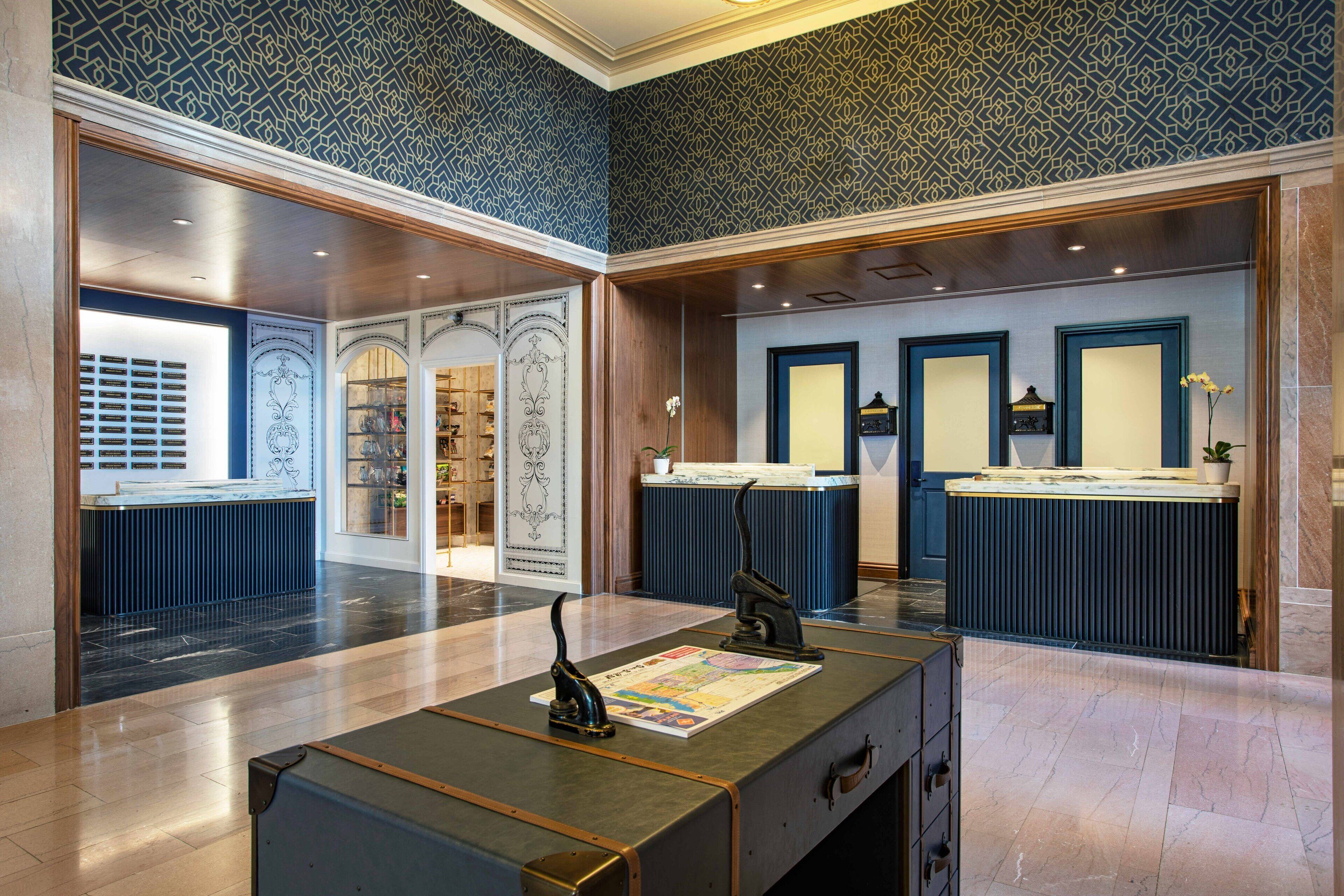 A lobby with a reception desk, patterned wallpaper, and a large mirror.