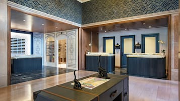 A lobby with a reception desk, patterned wallpaper, and a large mirror.