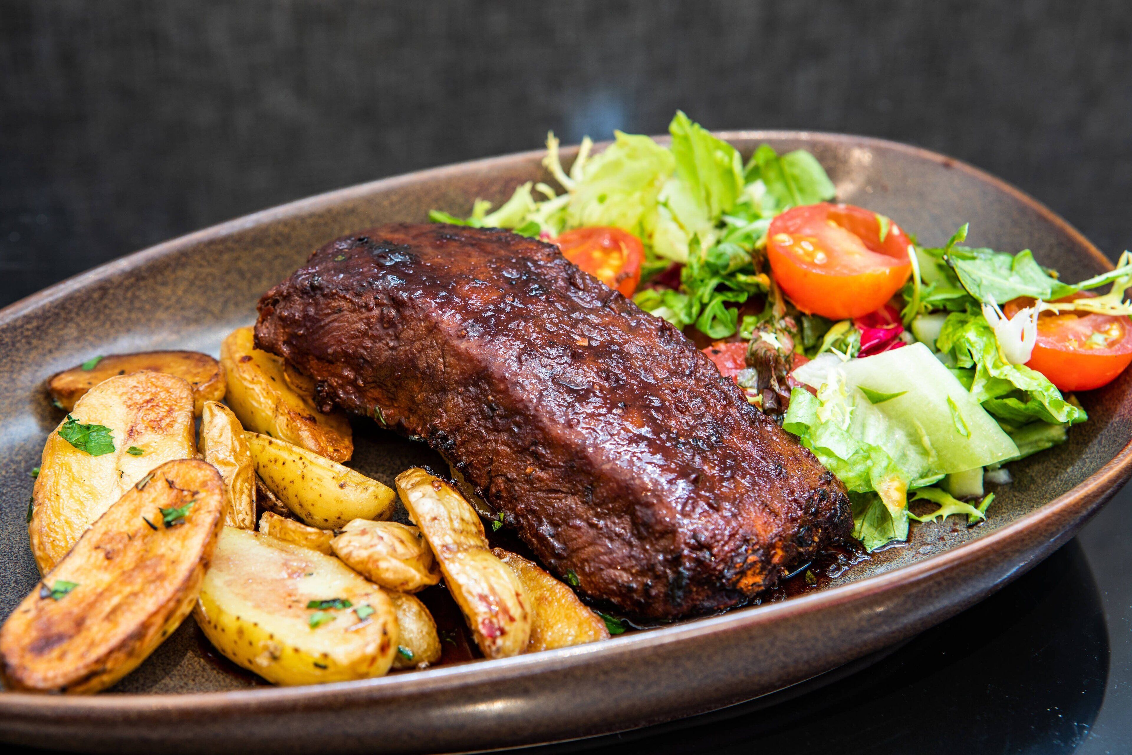 A plate with grilled meat, roasted potatoes, and a fresh salad.
