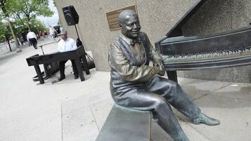 En bronsstaty som föreställer en man som sitter på en bänk och spelar piano.