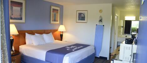 Una habitación de hotel con una cama, dos lámparas de noche, una mesita de noche, un aparador y un espejo.