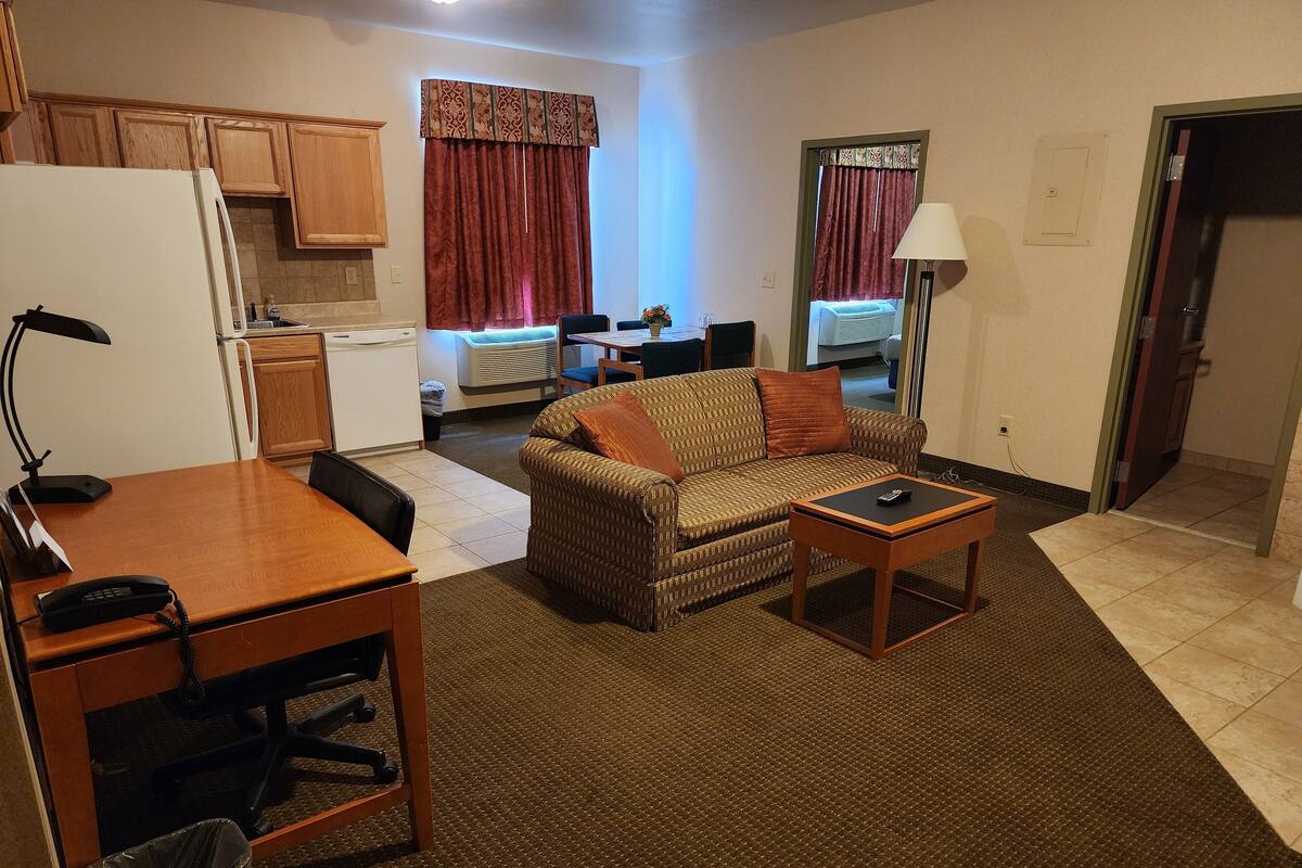 A compact living space with a kitchenette, a dining area, and a seating area with a sofa and a small table.