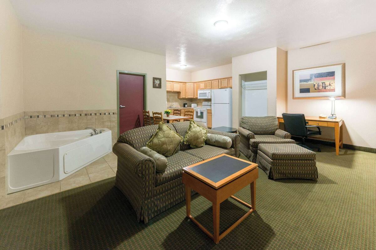 A compact living space with a kitchenette, a sofa set, a small table, and a bathtub.