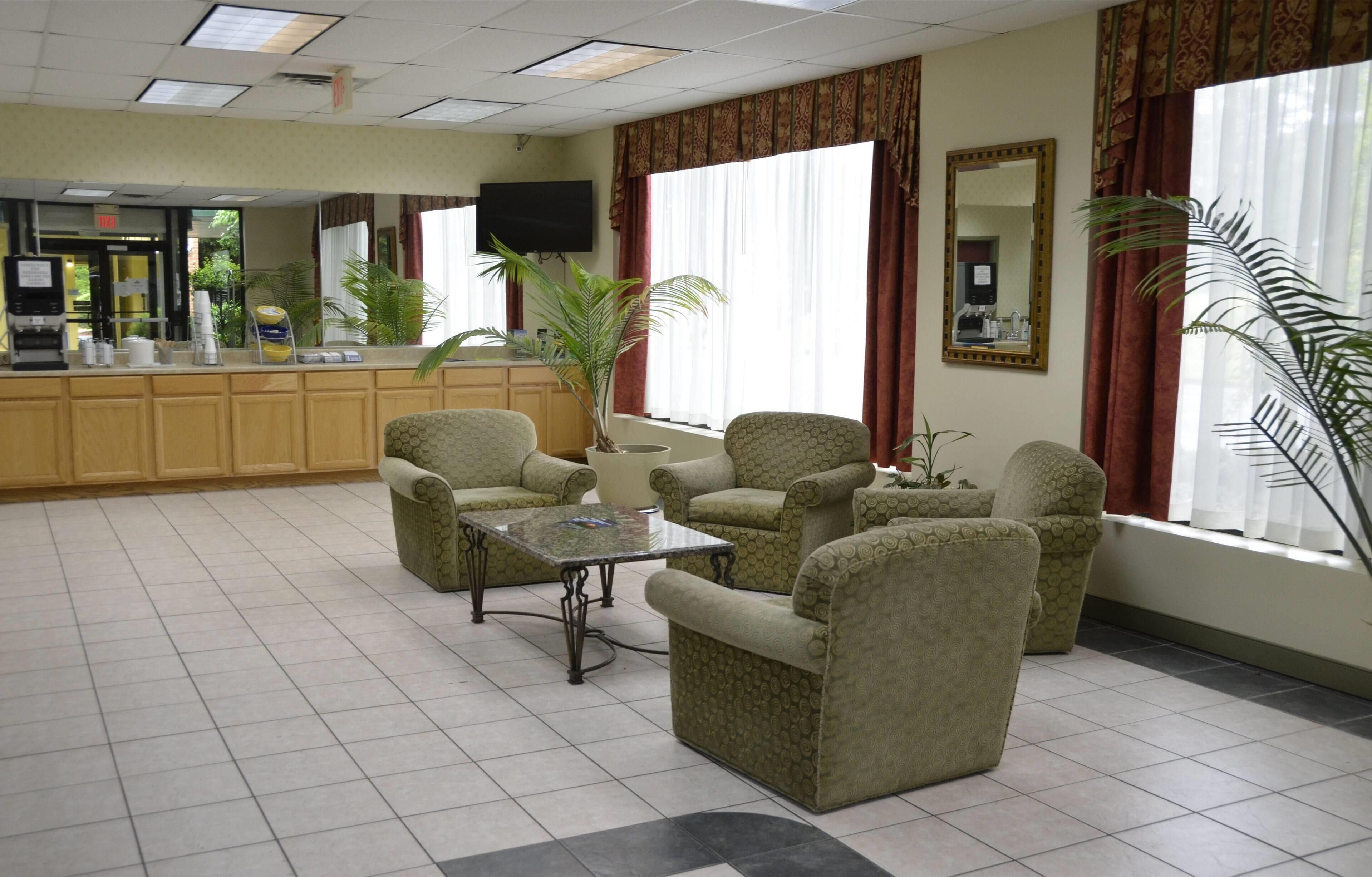 A hotel lobby with a reception desk, seating area, and large windows.