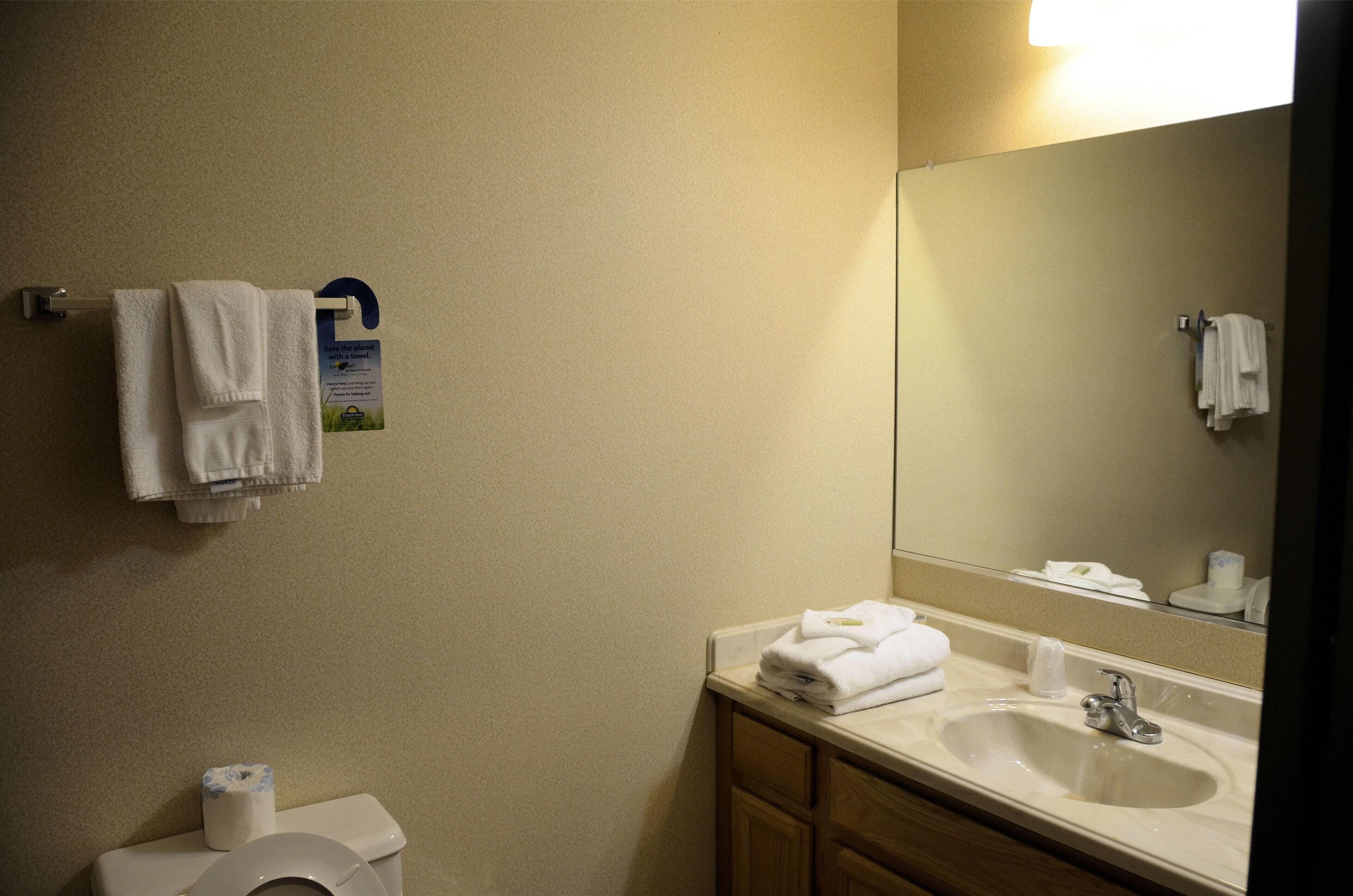 A bathroom with a toilet, sink, mirror, and towels.