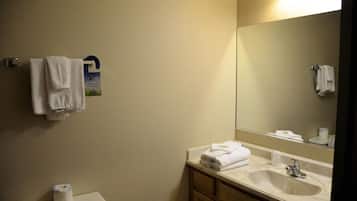 A bathroom with a toilet, sink, mirror, and towels.