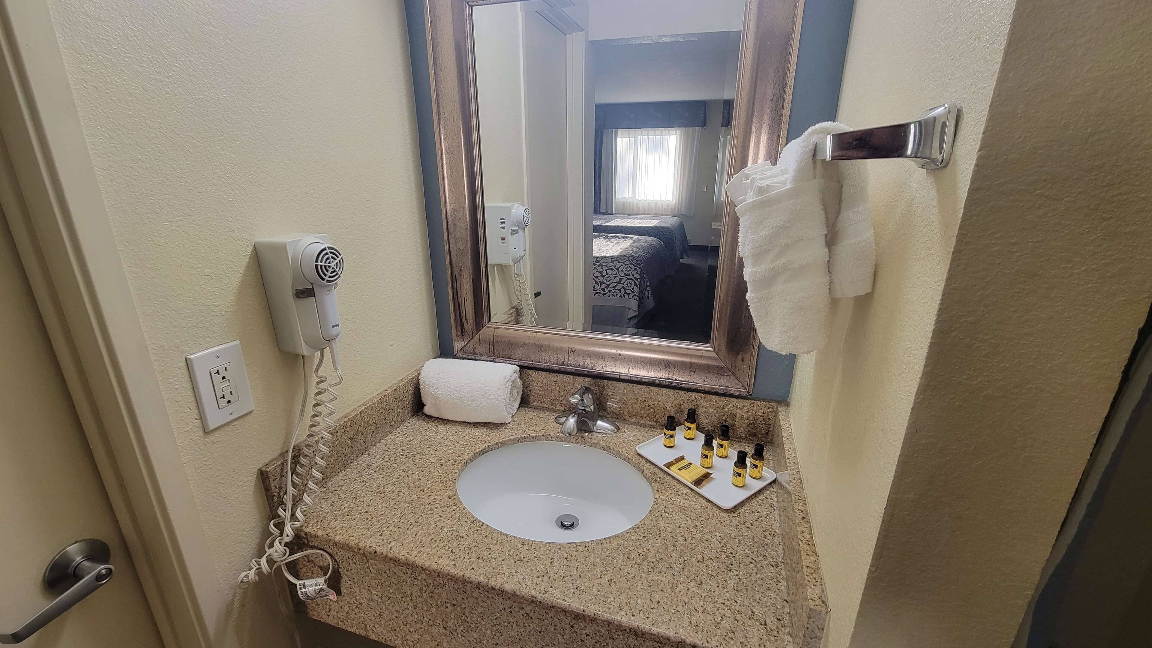 A bathroom with a sink, mirror, towel rack, and toiletries.