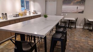 A modern kitchen with a large island, bar stools, and a view of the beach through a window. - SureStay Hotel by Best Western Chula Vista San Diego Bay (Chula Vista)