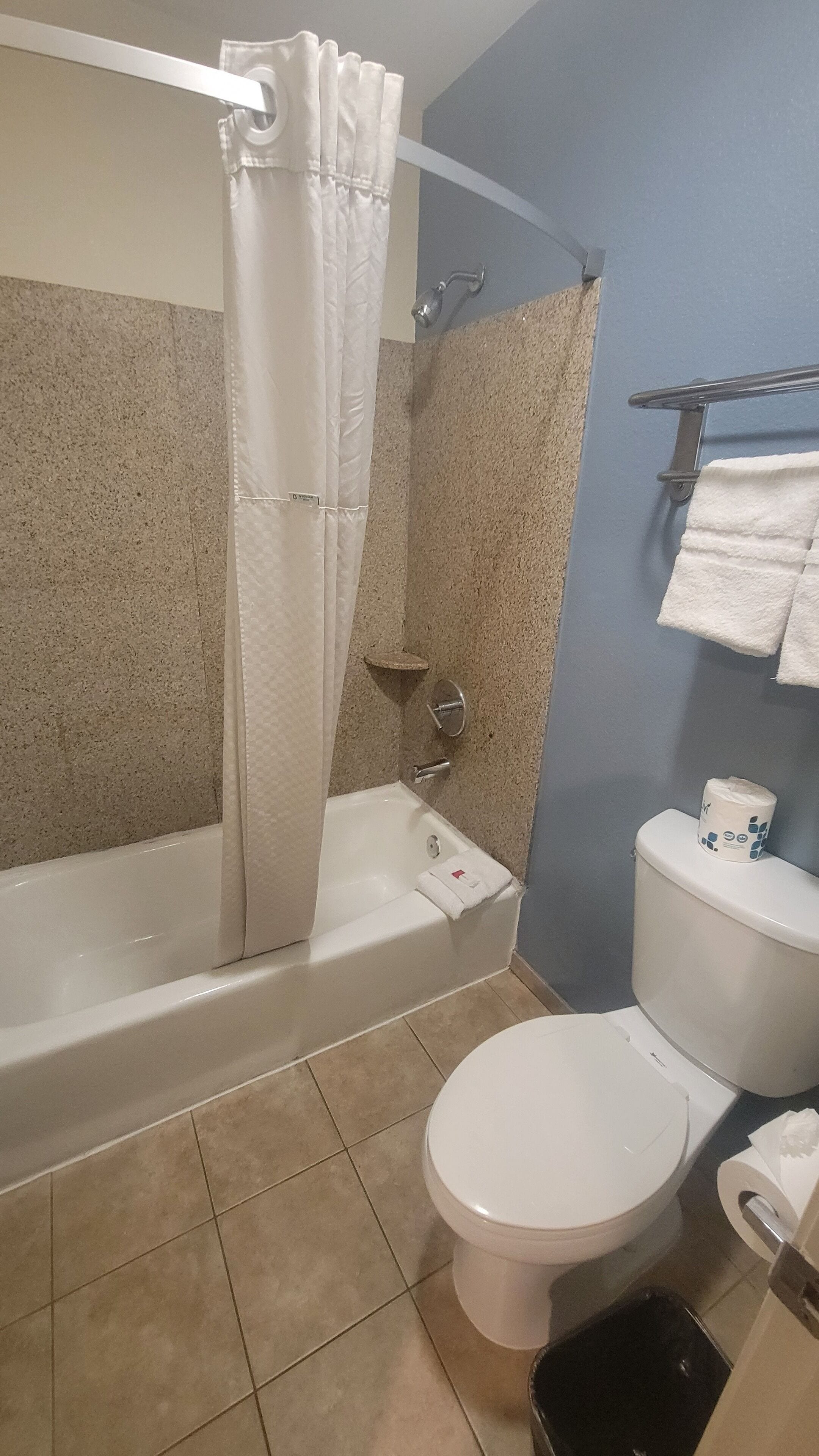 Un baño con bañera, inodoro y cortina de ducha.