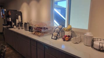 A breakfast bar with a coffee machine, toaster, and various food items.