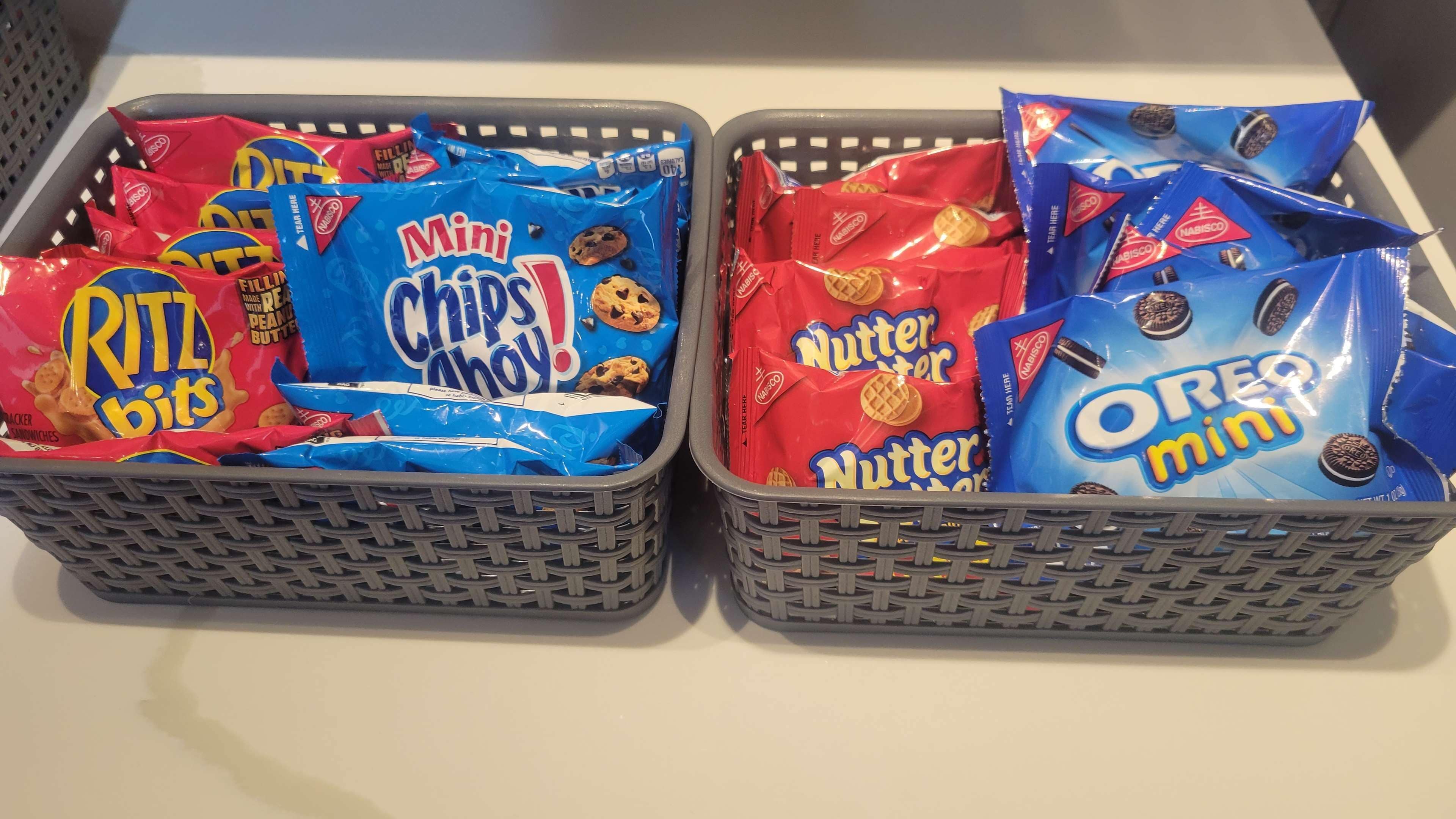 Two baskets filled with various snack items including Ritz bits, Mini chips, Nutter, and Oreo mini.
