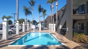 A rectangular swimming pool with clear blue water, surrounded by a metal fence and palm trees. - SureStay Hotel by Best Western Chula Vista San Diego Bay (Chula Vista)