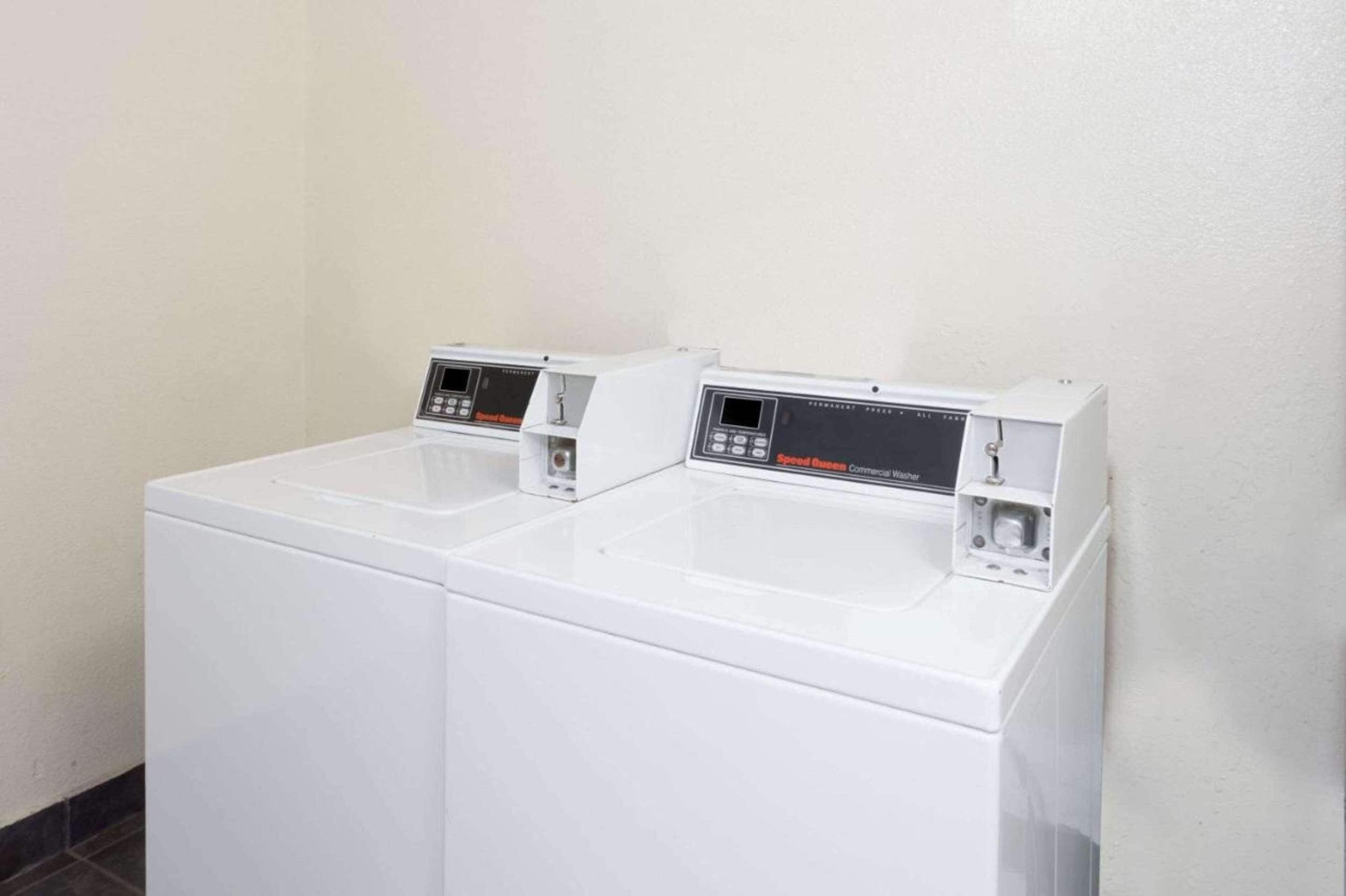 A row of white commercial washers with digital control panels.