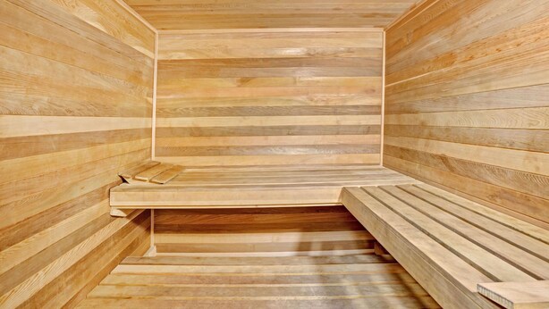 Eine Sauna mit Holzbänken und -wänden, mit schrägverdeckter Decke und einer Mittelbank.