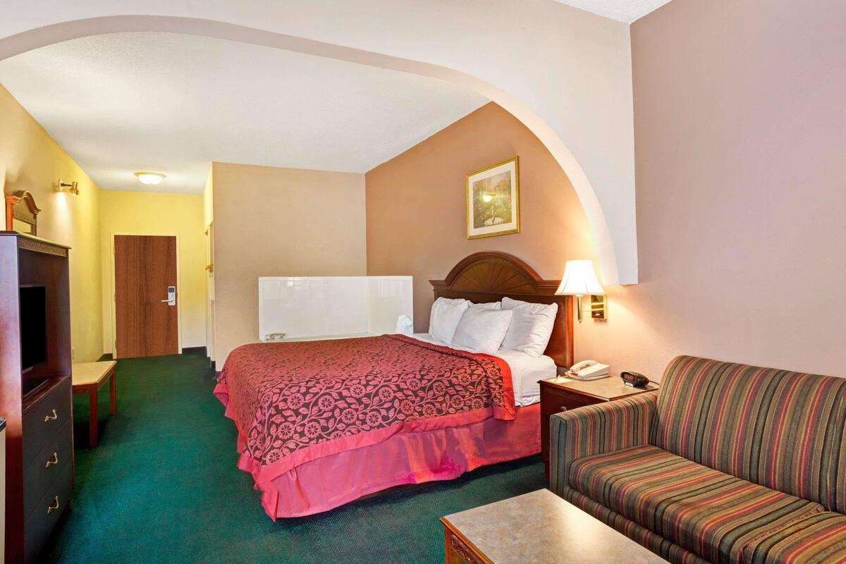 A hotel room with a bed, a sofa, a desk, and a television.