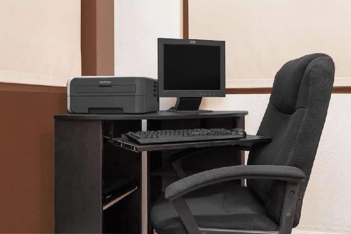 A computer desk with a monitor, keyboard, and printer.