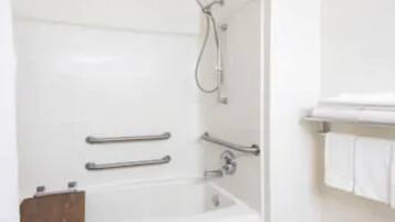 Ein modernes Badezimmer mit einer weißen Badewanne, Haltegriffen und einer Duschbrause.