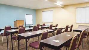 A conference room with tables and chairs, a whiteboard, and a projector screen.