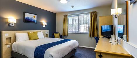 A hotel room with a bed, bedside table, TV, and a window with curtains.