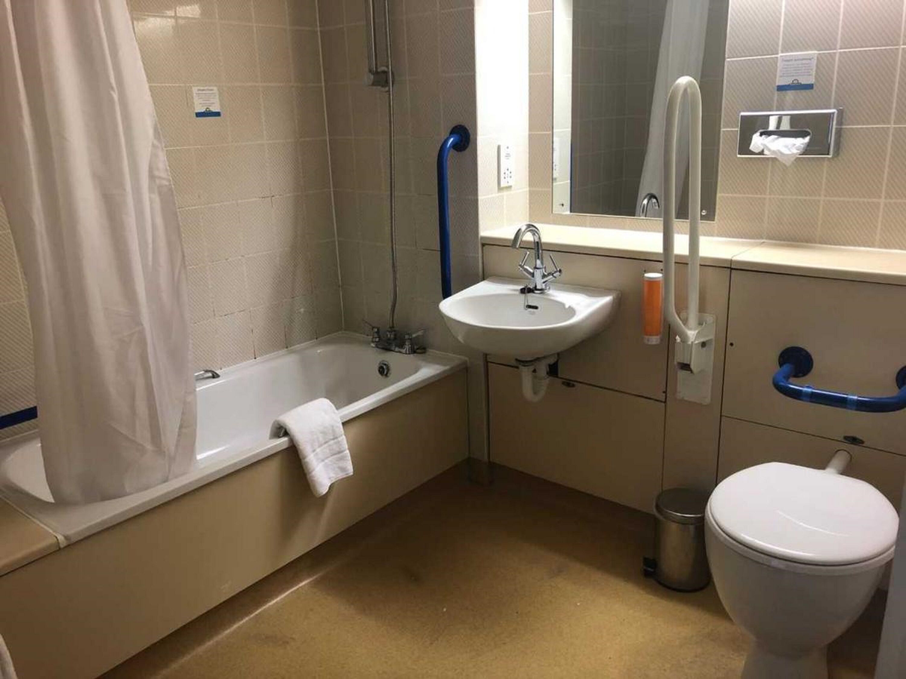 Et standard badeværelse med badekar, vask og toilet.