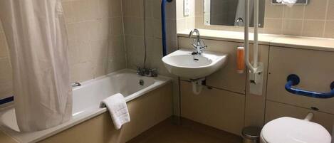 Et standard badeværelse med badekar, vask og toilet.